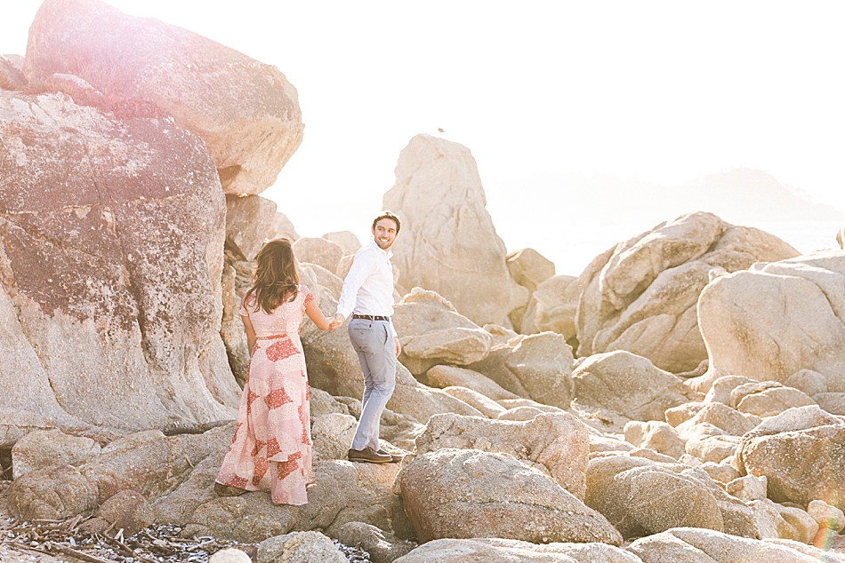Engaged couple walking along the Carmel rocks